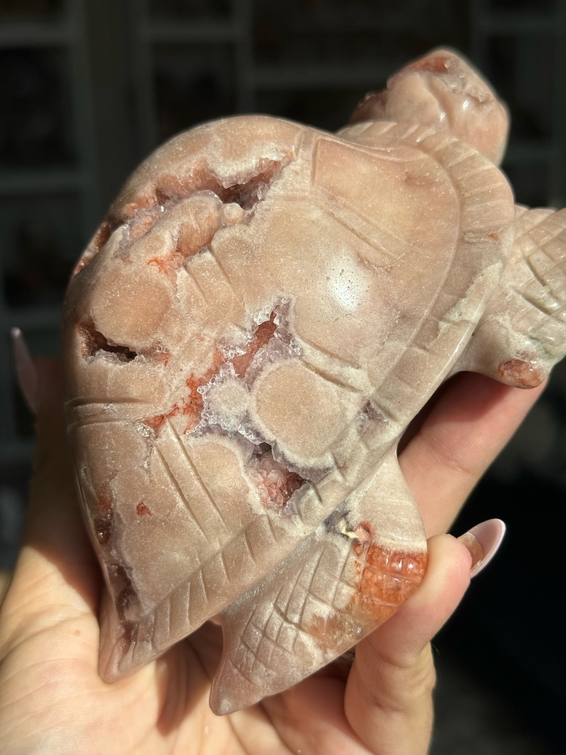 May include: A carved pink and red agate turtle figurine with a detailed shell and legs. The agate has a natural crystal formation with white and clear inclusions.