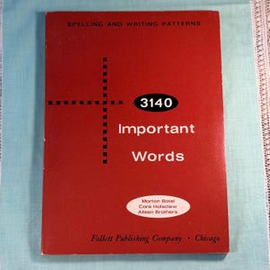 May include: A red educational book titled Spelling and Writing Patterns with the text 3140 Important Words. The cover features a black dashed cross graphic and an oval white label with the names Morton Botel, Cora Holsclaw, and Aileen Brothers.