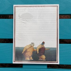 May include: A rectangular notepad with horizontal lines and a dark brown border. The bottom section features an illustration of two figures in swimsuits and hats wading in dark blue water, with one figure wearing a yellow patterned suit.