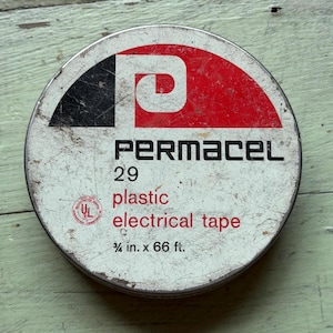 May include: A round metal tin for Permacel 29 plastic electrical tape. The lid is white with a red and black graphic logo, featuring the text Permacel 29 plastic electrical tape, a UL certification mark, and the dimensions 3/4 in. x 66 ft.