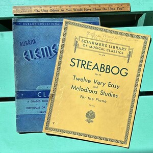 May include: Two music books, one blue and one yellow. The blue book is titled "Rubank Educational Elements of Music, Classroom Edition". The yellow book is titled "Schirmer's Library of Musical Classics, Vol. 478, Streabbog, Op. 63, Twelve Very Easy and Melodious Studies for the Piano, 75 cents".