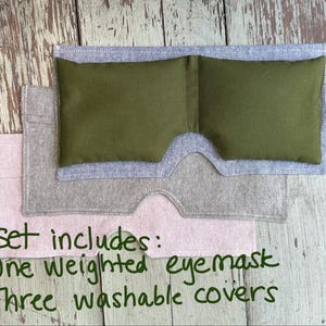 May include: A set of eye care products, including a green weighted eye mask and three washable covers in gray and pink. The text on the image reads: "Set includes: One weighted eye mask, Three washable covers."