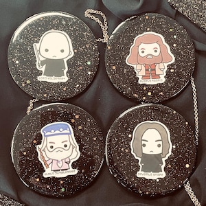 May include: Four black round compact mirrors with different character illustrations. The characters are Severus Snape, Remus Lupin, Albus Dumbledore, and Sirius Black. Each mirror has a black background with a silver trim.