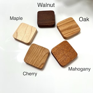 May include: Five square wooden samples arranged in a circle. The samples are labelled: Maple, Walnut, Oak, Cherry, and Mahogany. The wood grains vary in colour from light tan to dark brown. The text is in black, and the background is white.