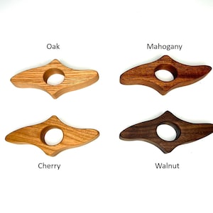 May include: Four wooden thumb page holders in oak, mahogany, cherry, and walnut. Each has a rounded hole for the thumb and a curved shape for holding pages open. The wood grains vary in color from light to dark.