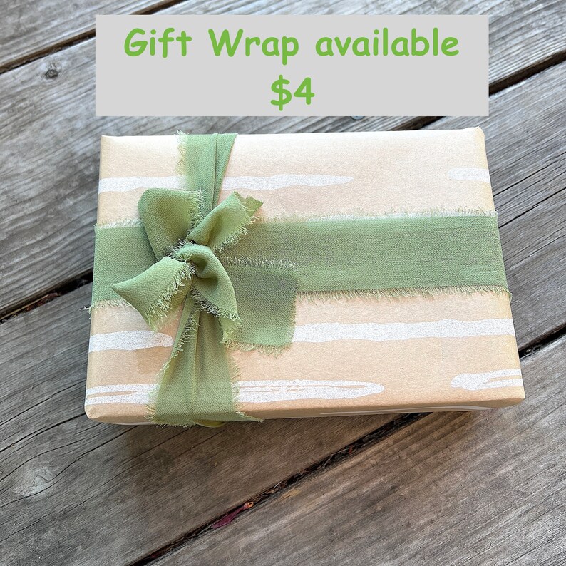 May include: A brown gift box with a green ribbon tied in a bow. The box has a white and brown striped pattern. The text "Gift Wrap available $4" is visible above the box.