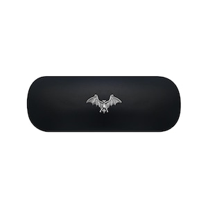 May include: A black, oval-shaped case with a silver bat emblem. The bat is depicted with outstretched wings, centered on the case. The case has a smooth, matte finish, and the bat emblem is detailed.