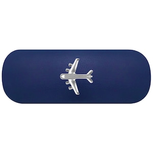 Könnte beinhalten: Ein marineblauer Geldklammer mit einem silbernen Flugzeugdesign. Die Klammer hat eine rechteckige Form mit abgerundeten Kanten und einer glatten, einfarbigen Oberfläche. Das Flugzeug ist detailliert und dreidimensional.