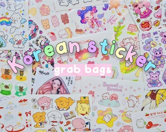 May include: Assortment of colorful Korean sticker grab bags featuring various cute cartoon characters, including animals, angels, and people. The bags are labeled with the text "Korean sticker grab bags".