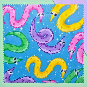 May include: A square fabric with a blue background featuring a pattern of colorful cartoon worms. The worms are in shades of pink, yellow, green, and purple, with white eyes and a starry background.
