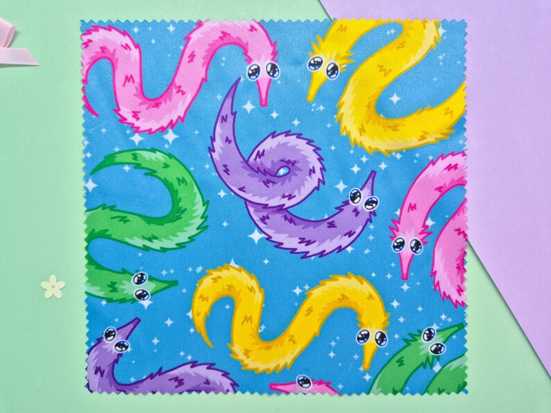 May include: A square fabric with a blue background featuring a pattern of colorful cartoon worms. The worms are in shades of pink, yellow, green, and purple, with white eyes and a starry background.