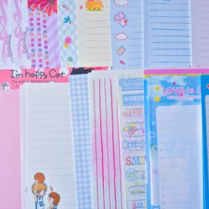 Puede incluir: Una colecci&oacute;n de hojas de papeler&iacute;a coloridas con varios dise&ntilde;os. Algunas hojas presentan papel rayado, mientras que otras tienen patrones decorativos como lazos, flores y personajes de dibujos animados. El texto "I'm happy Cat" y "LOVE is L" es visible.