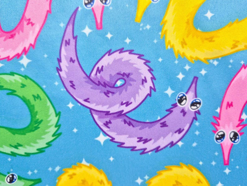 May include: A repeating pattern of cartoon worm illustrations in pink, purple, yellow, and green on a light blue background. The worms have large, expressive eyes and are set against a backdrop of white star shapes.
