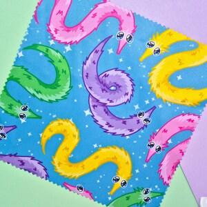 May include: A square fabric with a blue background featuring a pattern of colorful cartoon worms. The worms are in shades of pink, yellow, green, and purple, with white eyes and a starry background.