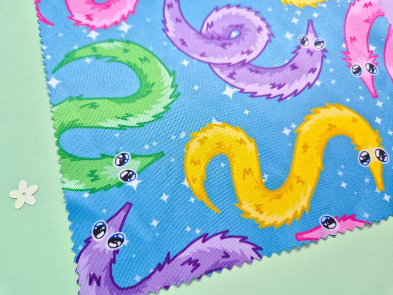 May include: A blue fabric with a repeating pattern of colorful cartoon worms with big eyes. The worms are in shades of pink, purple, yellow, and green, with a starry background.