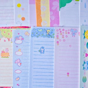 Puede incluir: Una colecci&oacute;n de hojas de papeler&iacute;a coloridas con varios dise&ntilde;os. Algunas hojas presentan papel rayado con ilustraciones de animales, nubes y estrellas. Otras hojas tienen patrones florales, lunares y bordes decorativos.