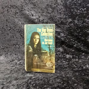 May include: A vintage paperback book titled "The Van Dyne Collection" by Marianne de Jay Scott. The cover features a woman's portrait against a blue and green backdrop. The book has the "Easy Eye" logo.