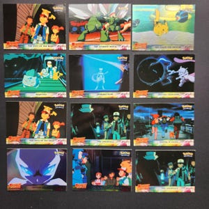 Peut inclure: Une collection de douze cartes à collectionner Pokémon rectangulaires présentant des scènes du film Mewtwo Strikes Back. Chaque carte affiche des personnages animés colorés, dont Pikachu, Sacha et Mewtwo, avec des titres imprimés en bas.
