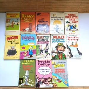May include: A collection of fourteen vintage paperback comic strip books featuring titles such as Marmaduke, Ziggy, B.C., Andy Capp, Hägar the Horrible, Belvedere, Mad's Don Martin, and Beetle Bailey, displayed in a grid with colourful illustrated covers.