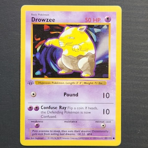 Puede incluir: Una carta coleccionable de Drowzee con una ilustración de criatura amarilla y marrón, 50 HP y un símbolo de energía psíquica. El texto incluye los ataques Pound y Confuse Ray, Hypnosis Pokémon, altura 1 m, peso 32 kg y copyright 1999.