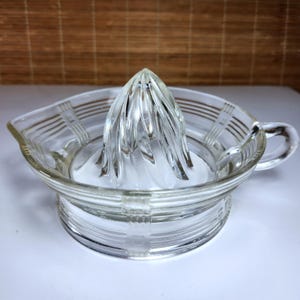 Peut inclure: Presse-agrumes en verre transparent avec un presse-agrumes et une poignée. Le presse-agrumes a un design nervuré et est conçu pour extraire le jus des agrumes. Le presse-agrumes est en verre transparent.
