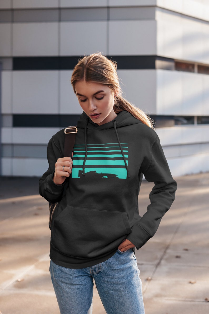 May include: A black hoodie with a turquoise and black graphic of a race car on a striped background. The hoodie has a drawstring hood and a kangaroo pocket.
