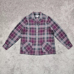 Könnte beinhalten: Ein karierter Blazer in Lila, Grau und Rosa. Die Jacke hat einen Reverskragen, drei Knöpfe und zwei Vordertaschen. Der Stoff hat ein klassisches Karomuster.