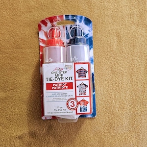 May include: A mini tie-dye kit with two bottles, one red and one gray, packaged on a patriotic-themed card. The kit includes instructions and is labeled "Patriot" with the text "Just add water".