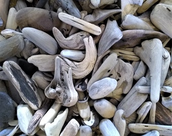 May include: A collection of weathered driftwood pieces in various shapes and sizes. The wood tones range from light beige to dark gray, with some pieces showing natural textures and knots. The arrangement suggests a natural, coastal theme.