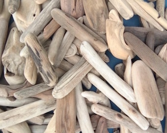 May include: A collection of assorted driftwood pieces in various shades of brown, tan, and grey. The pieces vary in length, thickness, and texture, featuring smooth, weathered surfaces and irregular shapes, piled together in a dense, overlapping arrangement.
