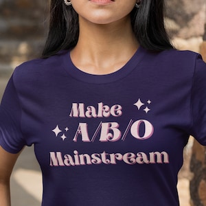 May include: A navy blue t-shirt with the text "Make A/B/O Mainstream" in pink lettering with stars on either side of the text.