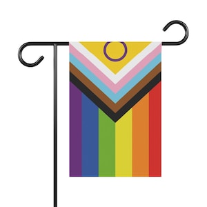 May include: A garden flag with a rainbow design, including a purple circle with a yellow center, representing the Progress Pride flag.