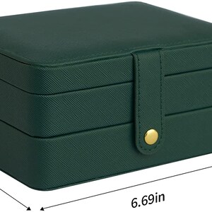 May include: A green three-tiered jewellery box with a gold buckle closure. The box measures 6.69 inches long, 4.72 inches wide, and 3.15 inches high.