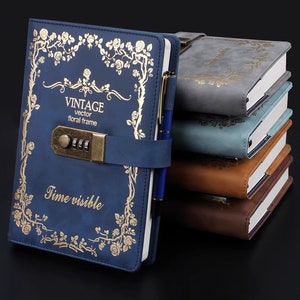 May include: A collection of vintage journals in shades of blue, grey, and brown. The front blue journal has a gold floral design, the words "VINTAGE vector floral frame Time visible", and a combination lock. A pen is inserted into the spine of the journal.