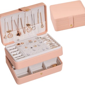 May include: A pink two-tiered jewellery box with a hinged lid and a pull-out drawer. The top tier has slots for necklaces, earrings, and rings. The bottom tier has compartments for rings and other small items.