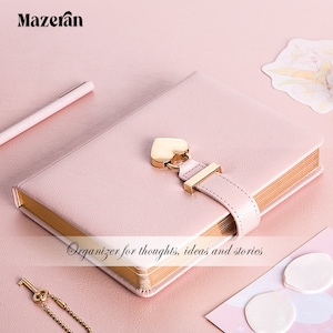 Peut inclure: Un journal relié en cuir rose avec une serrure et une clé en forme de cœur dorées. Le journal a une bordure dorée et le texte "Organisateur pour les pensées, les idées et les histoires" est imprimé sur la couverture.