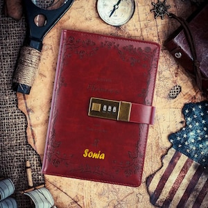 May include: A red leather journal with a floral design and a combination lock. The journal has the word "Flowers" printed on the front and the name "Sonia" embossed in gold.