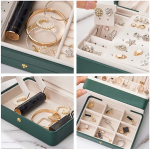 May include: A green jewellery box with a gold clasp. The box has a velvet interior with compartments for rings, earrings, necklaces, and other jewellery. The box is open and the compartments are filled with jewellery.