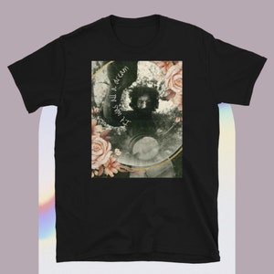 May include: Black t-shirt with a graphic of a person in a circle with flowers and the text "It was all a dream".