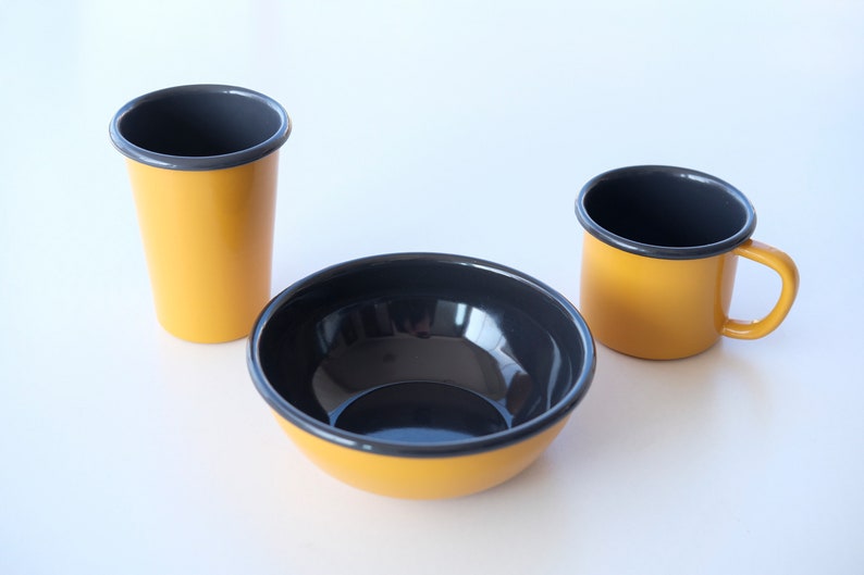 A sophisticated yellow enamelware set with contrasting anthracite rims, perfect for stylish dining, comprising a bowl, mug, and tumbler.