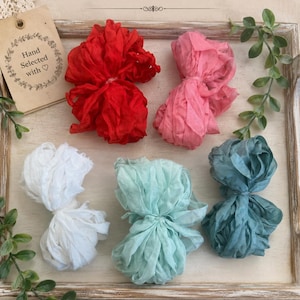 May include: Five bundles of crinkled seam ribbons in red, pink, white, light green, and dark teal. A tan tag reads Hand Selected with a heart symbol. Text on the image includes Pretty Crinkled Seam Ribbons and Add a Touch of Vintage Charm.