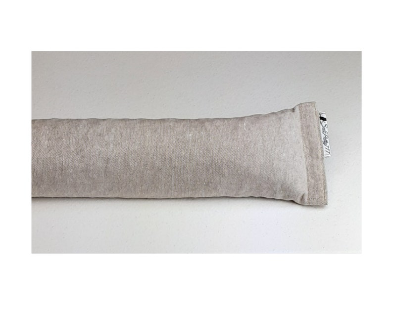 Op de afbeelding: Een lang, beige, rechthoekig kussen met een wit label waarop "Seagrass 777" staat.