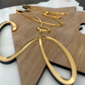May include: A wooden sign with the word "Sofia" written in gold cursive lettering. The sign is shaped like a star and has a black border.