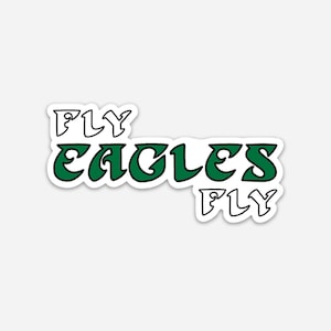 May include: A sticker with the text "FLY EAGLES FLY" in a green and white design. The word "EAGLES" is in a bold, green, bubble-style font, while "FLY" is in a white, outlined font. The sticker has a white border.