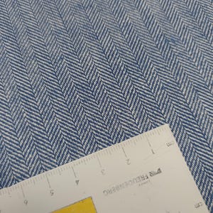 Könnte beinhalten: Nahaufnahme eines blau-weißen Fischgrätenstoffs mit einem Lineal, das 12,7 cm misst. Das Lineal ist mit "FREUDENBERG" beschriftet und hat Zentimetermarkierungen.