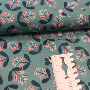 Könnte beinhalten: Tealfarbener Stoff mit einem sich wiederholenden Muster aus rosa und grünen Blättern und kleinen Vögeln. Der Stoff ist umgeklappt und ein Lineal ist in der unteren rechten Ecke sichtbar.