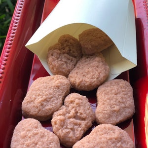 May include: A red tray with a white paper bag filled with chicken nuggets. The nuggets are arranged in a circle on the tray.