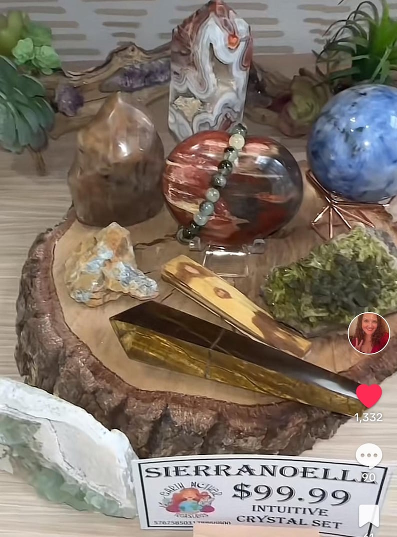 May include: A collection of crystals and stones on a wooden display stand. The set includes a large red and brown crystal, a smaller brown crystal, a green crystal, a blue crystal, a yellow crystal, and a clear crystal. The crystals are arranged in a circle on the stand. The stand is made of wood and has a natural finish. The crystals are all different shapes and sizes. The set is priced at $99.99 and is called "Intuitive Crystal Set".