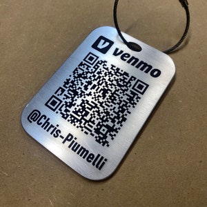 May include: A silver metal keychain with a black Venmo logo and a QR code. The text "@Chris-Piumelli" is engraved below the QR code.