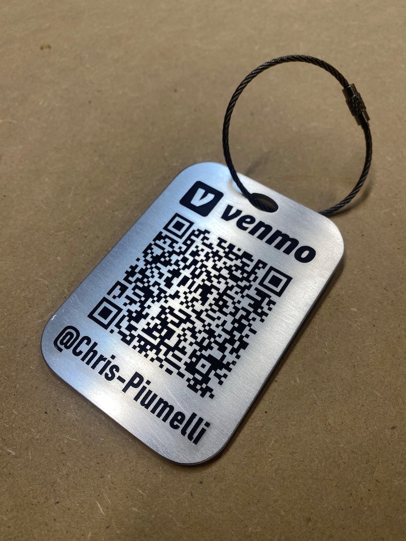 May include: A silver metal keychain with a black Venmo logo and a QR code. The text "@Chris-Piumelli" is engraved below the QR code.
